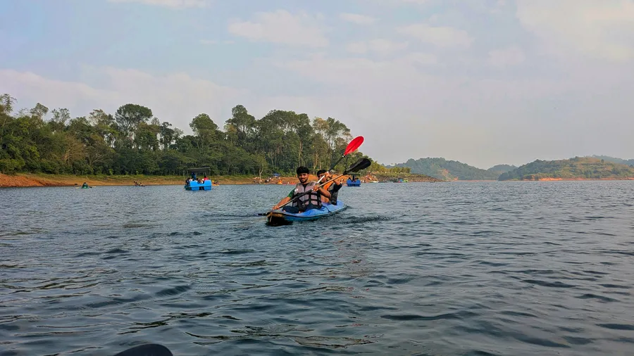 Familia disfrutando del kayak en un lago tranquilo rodeado de colinas boscosas.