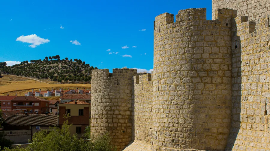 Paredes de un antiguo castillo de piedra bajo un cielo azul brillante.